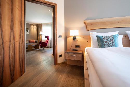 a bedroom with a bed and a mirror and a desk at Vitalpina Hotel Waldhof in Rablà