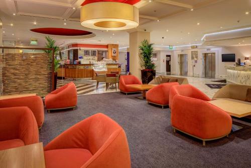 uma área de espera com cadeiras e mesas cor-de-laranja no átrio em Hilton Leeds City em Leeds