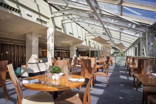 um restaurante vazio com mesas e cadeiras de madeira em Hilton Leeds City em Leeds