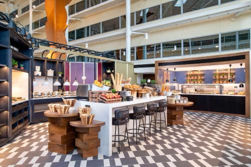a restaurant with a counter and stools at Hilton London Heathrow Airport in Hillingdon