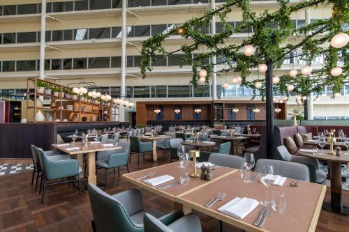 a restaurant with tables and chairs and a building at Hilton London Heathrow Airport in Hillingdon