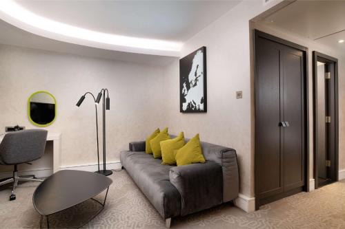 a living room with a couch with yellow pillows at Hilton London Heathrow Airport in Hillingdon