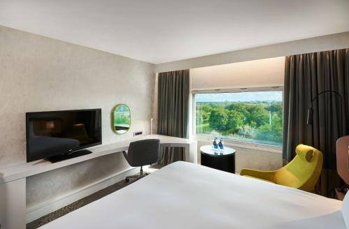 a hotel room with a bed and a large window at Hilton London Heathrow Airport in Hillingdon