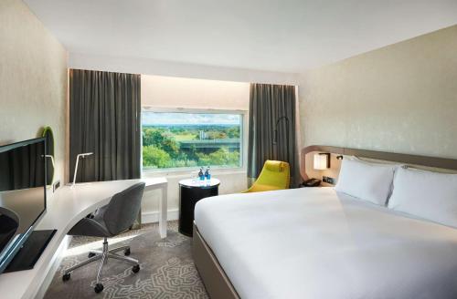 a hotel room with a large bed and a window at Hilton London Heathrow Airport in Hillingdon