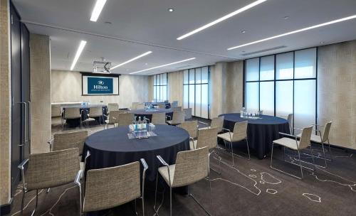 a conference room with tables and chairs and a screen at Hilton London Heathrow Airport in Hillingdon
