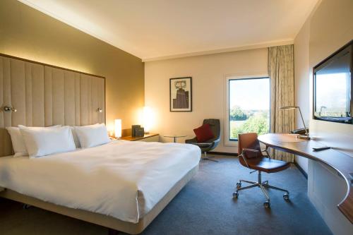 ein Hotelzimmer mit einem großen Bett und einem Schreibtisch in der Unterkunft Hilton London Heathrow Airport Terminal 5 in Hillingdon