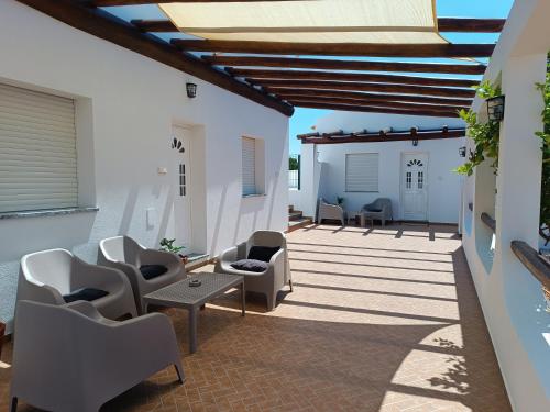 eine Terrasse mit weißen Stühlen sowie einem Tisch und Stühlen in der Unterkunft Casa Zeferino in Ferragudo