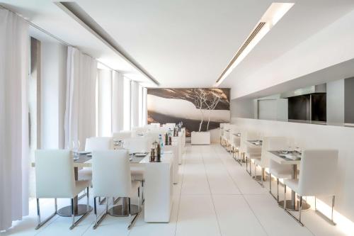 een eetkamer met witte tafels en witte stoelen bij DoubleTree by Hilton Lisbon Fontana Park in Lissabon