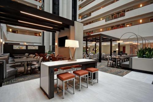 un ristorante con sgabelli, tavoli e sedie di Embassy Suites Little Rock a Little Rock