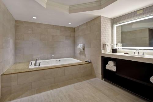 a bathroom with a tub and two sinks and a mirror at Embassy Suites Little Rock in Little Rock