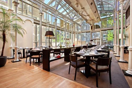 a restaurant with tables and chairs and windows at Hilton London Euston in London