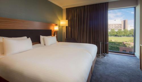 a large bed in a hotel room with a large window at Hilton Liverpool City Centre in Liverpool