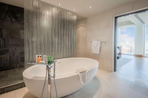 uma casa de banho branca com uma banheira e um chuveiro em Hilton Liverpool City Centre em Liverpool