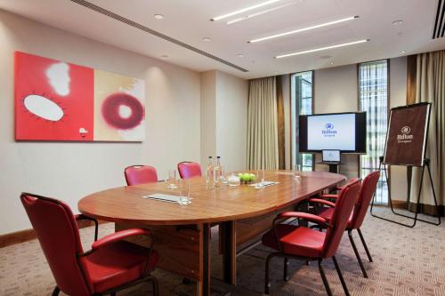 a conference room with a wooden table and red chairs at Hilton Liverpool City Centre in Liverpool