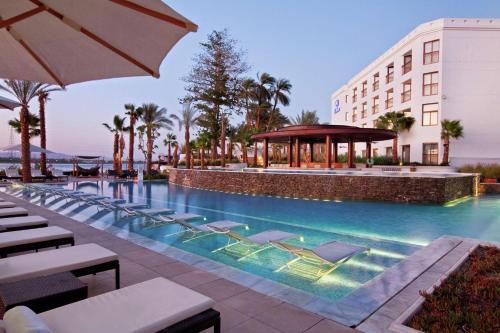 une piscine avec des chaises longues et un bâtiment dans l'établissement Hilton Luxor Resort & Spa, à Louxor