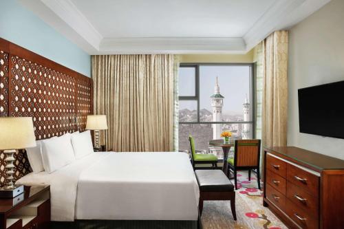 a hotel room with a bed and a desk and a window at Hilton Suites Jabal Omar Makkah in Makkah