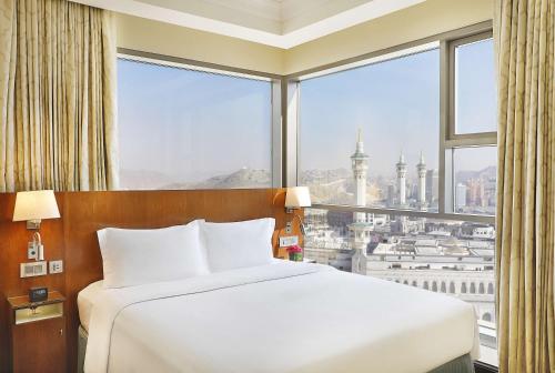 a bed in a room with a large window at Hilton Suites Jabal Omar Makkah in Makkah