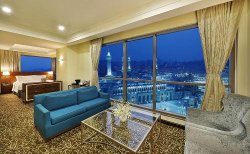a hotel room with a blue couch and a large window at Hilton Suites Jabal Omar Makkah in Makkah