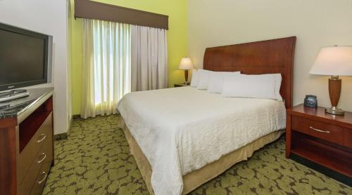 a hotel room with a bed and a flat screen tv at Hilton Garden Inn Macon/Mercer University in Macon