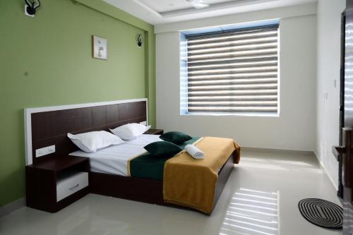a bedroom with a bed with green walls and a window at The Green Room Residency in Padinjarathara