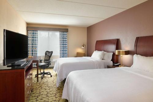 a hotel room with two beds and a flat screen tv at Hilton Garden Inn Hershey in Hummelstown