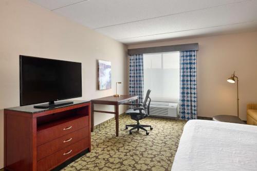 a hotel room with a bed and a desk with a television at Hilton Garden Inn Hershey in Hummelstown