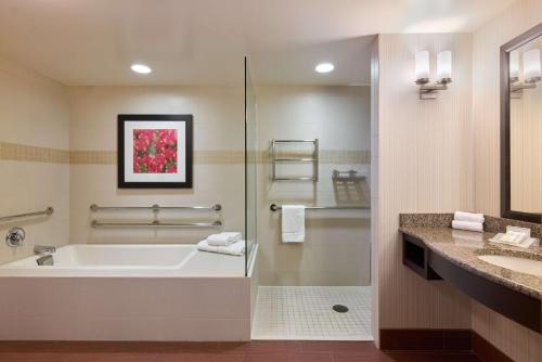a bathroom with a tub and a shower and a sink at Hilton Garden Inn Hershey in Hummelstown
