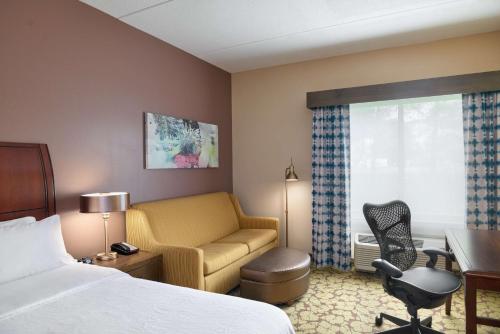 a hotel room with a bed and a desk and a chair at Hilton Garden Inn Hershey in Hummelstown