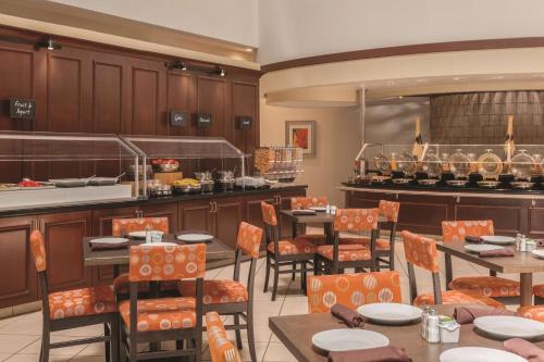 a restaurant with tables and chairs and a kitchen at Embassy Suites by Hilton Orlando International Drive ICON Park in Orlando