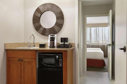 baño con lavabo, espejo y cama en Embassy Suites by Hilton Orlando International Drive ICON Park, en Orlando