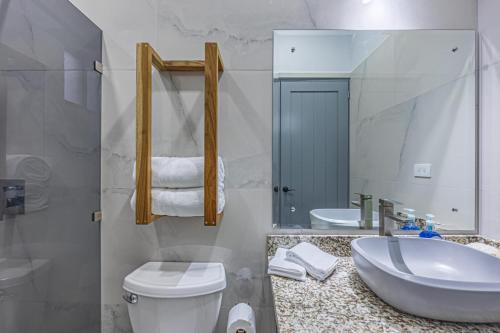 ein Badezimmer mit einem Waschbecken, einem WC und einem Spiegel in der Unterkunft Casamar Villa's in Uvita