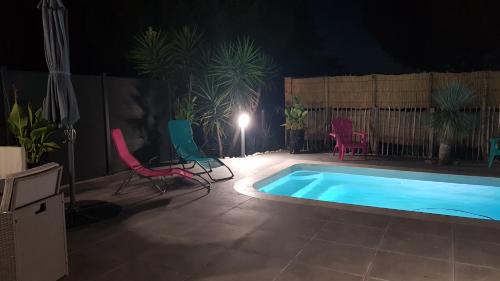 - une piscine avec des chaises, une table et une lumière dans l'établissement Domaine de L'Outarde Canepetiére Gîte A, à Aigues-Mortes