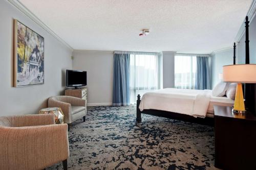 Embassy Suites Montgomery - Hotel & Conference Center في مونتغومري: غرفه فندقيه بسرير وكرسي