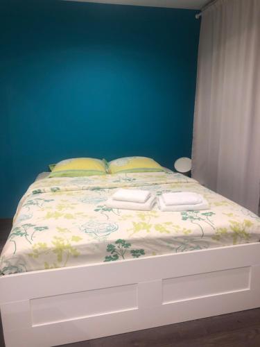 uma cama com duas almofadas e uma parede azul em Grand studio em Meythet