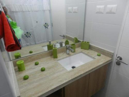 baño con lavabo con bolas verdes en Departamento resort lagunas del mar, en La Serena