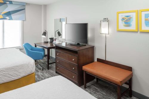 Habitación de hotel con cama y escritorio con TV. en Hampton Inn & Suites Miami-Doral Dolphin Mall en Miami