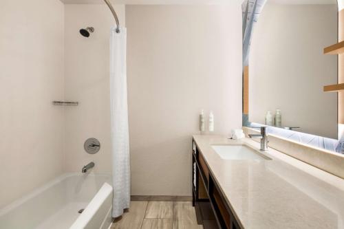 a white bathroom with a tub and a sink at Hilton Garden Inn Monterey in Monterey
