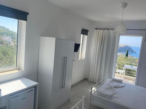 a white kitchen with a refrigerator and a window at Penelope & Michael Rooms in Himare