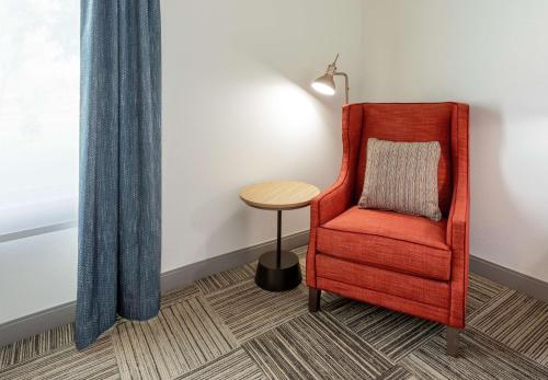 a room with a red chair and a table at Hilton Garden Inn Minneapolis/Bloomington in Bloomington