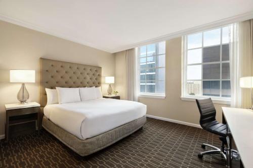 um quarto de hotel com uma cama e duas janelas em Hilton New Orleans / St. Charles Avenue em Nova Orleans