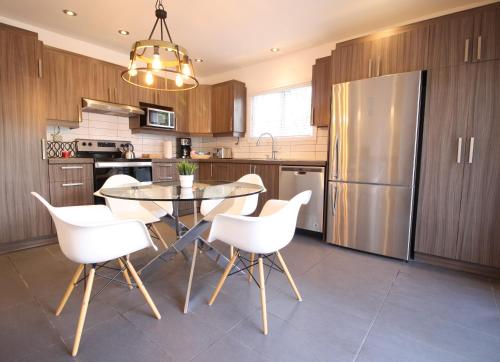 a kitchen with a glass table and white chairs at Luxueux - Deco moderne, Rosemont in Montréal