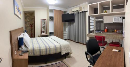 um quarto de hotel com uma cama e uma cozinha em Residencial Flat Villa Rosa em Itapetininga