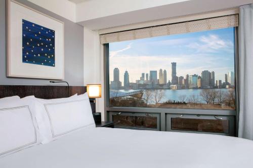 a bedroom with a large window with a view of the city at Conrad New York Downtown in New York