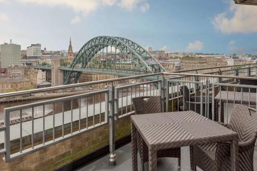 a table and chairs on a balcony with a bridge at Hilton Newcastle Gateshead in Newcastle upon Tyne