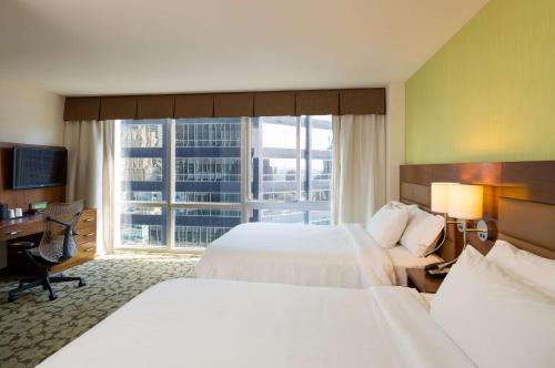 Cette chambre comprend deux lits, un bureau et une fenêtre. dans l'établissement Hilton Garden Inn New York Manhattan Midtown East, à New York