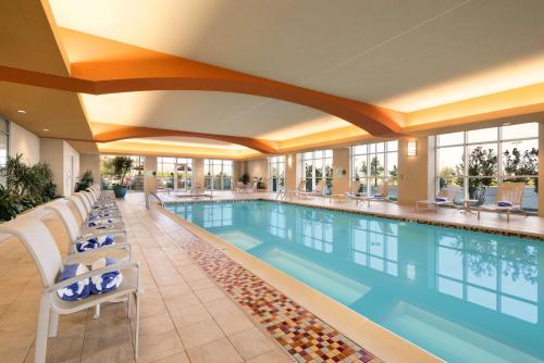a pool in a hotel with chairs and a swimming pool at Embassy Suites by Hilton Norman Hotel & Conference Center in Norman