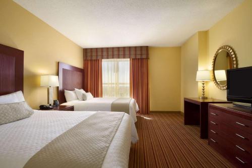 a hotel room with two beds and a flat screen tv at Embassy Suites by Hilton Norman Hotel & Conference Center in Norman