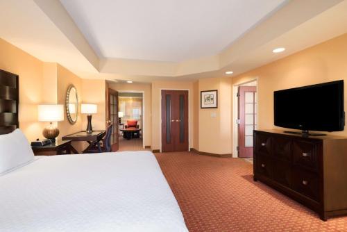 a hotel room with a bed and a flat screen tv at Embassy Suites by Hilton Norman Hotel & Conference Center in Norman