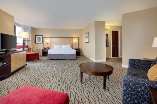 a hotel room with a bed and a living room at Hilton Rosemont Chicago O'Hare in Rosemont