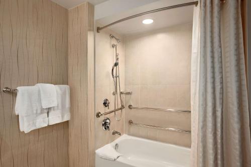 a bathroom with a shower and a toilet and a sink at Hilton Rosemont Chicago O'Hare in Rosemont